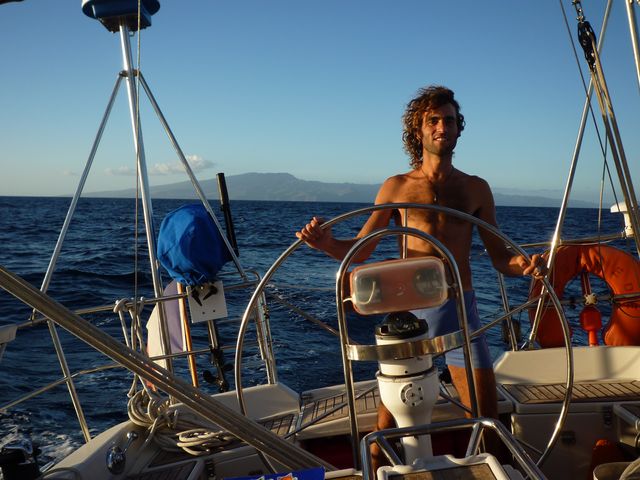 13 May 2010<br>At the helm, the island of Nuku Hiva in the Marquesas back plan.Voilier Tago Mago, crossing between the Marquesas Islands and Tuamotu
